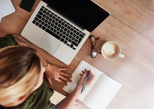 Office space with computer, cup of coffee, and open journal