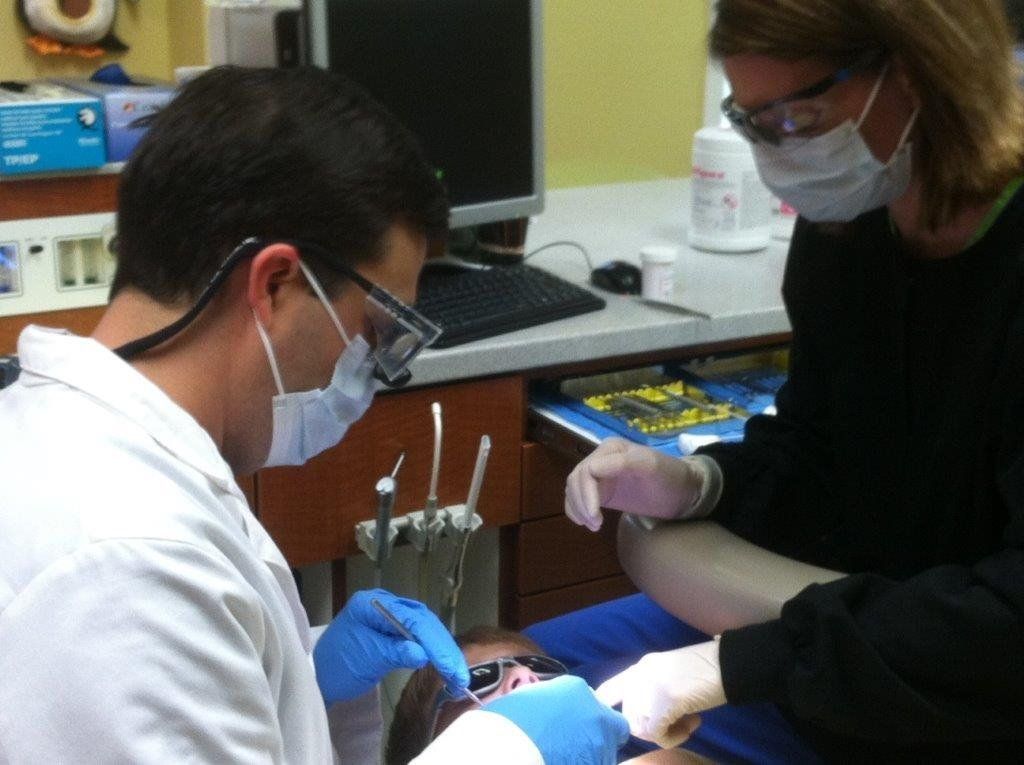 A dentist and dental assistant work together on a patient in a clean, professional clinic setting.