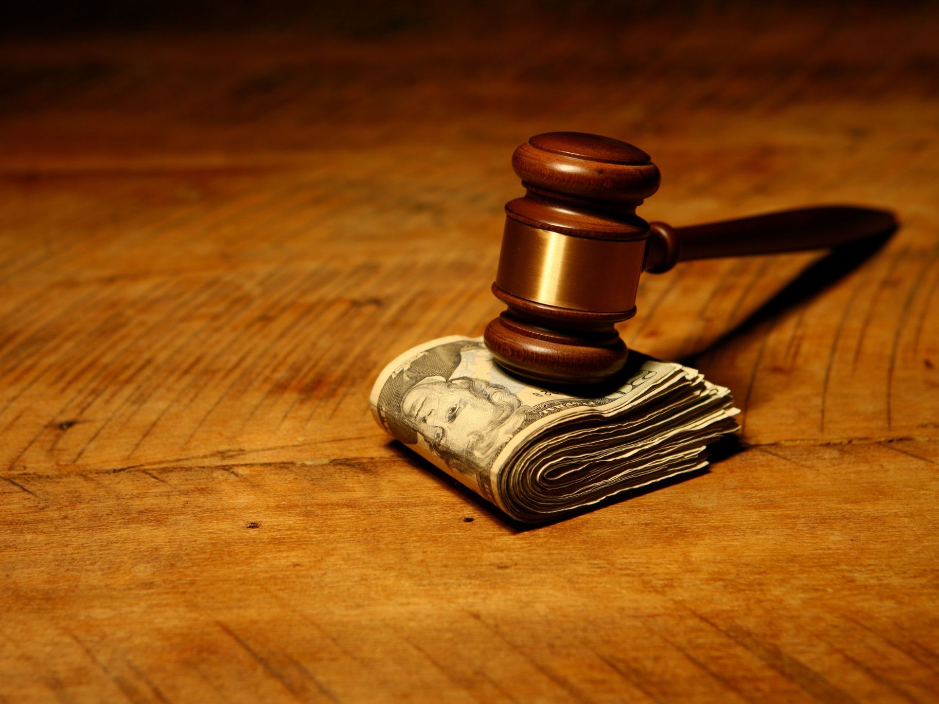 Gavel on money laying wooden table