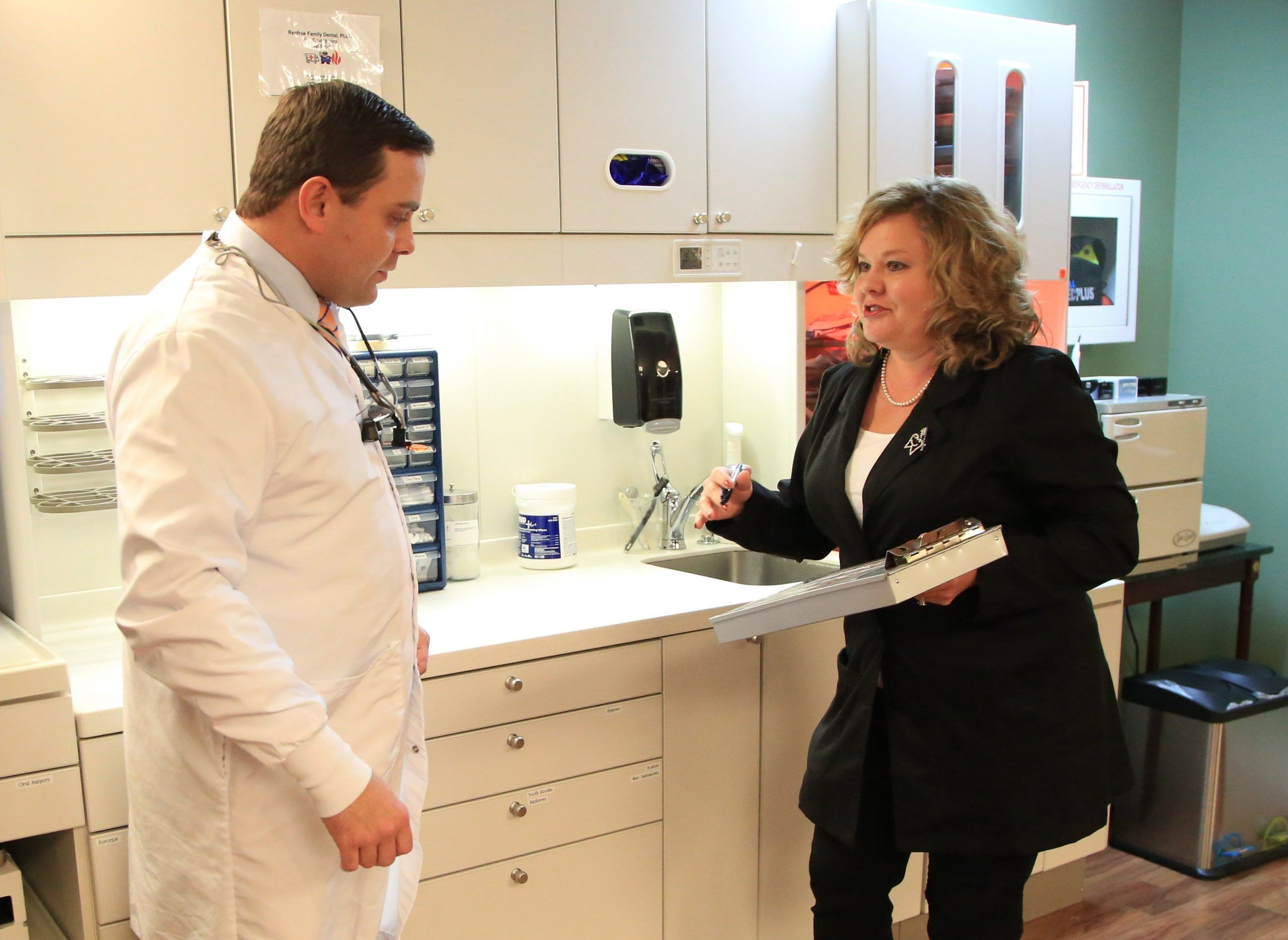 Olivia Wann during a mock audit speaking with a dentist. She is holding a pen and a clipboard. 